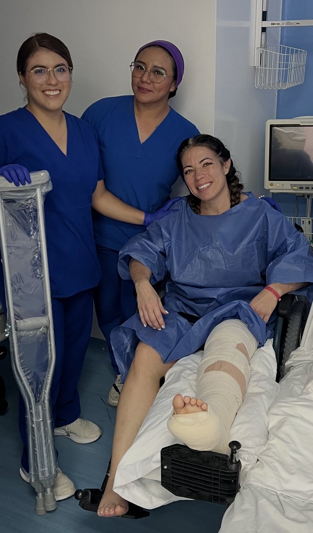 Felecia in a wheelchair with a bandaged leg in the hospital